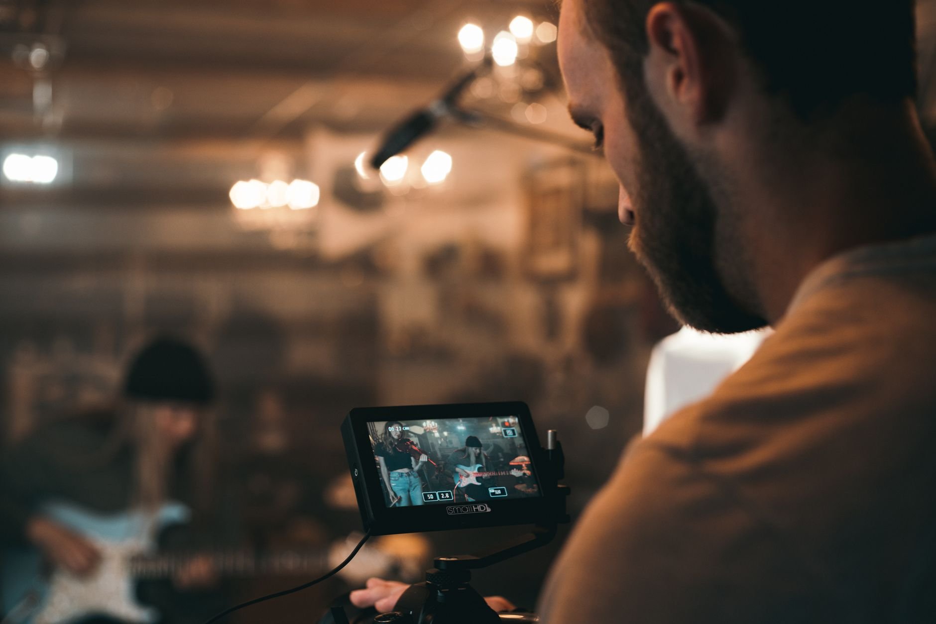 Filmmaker capturing a live music performance indoors on set.