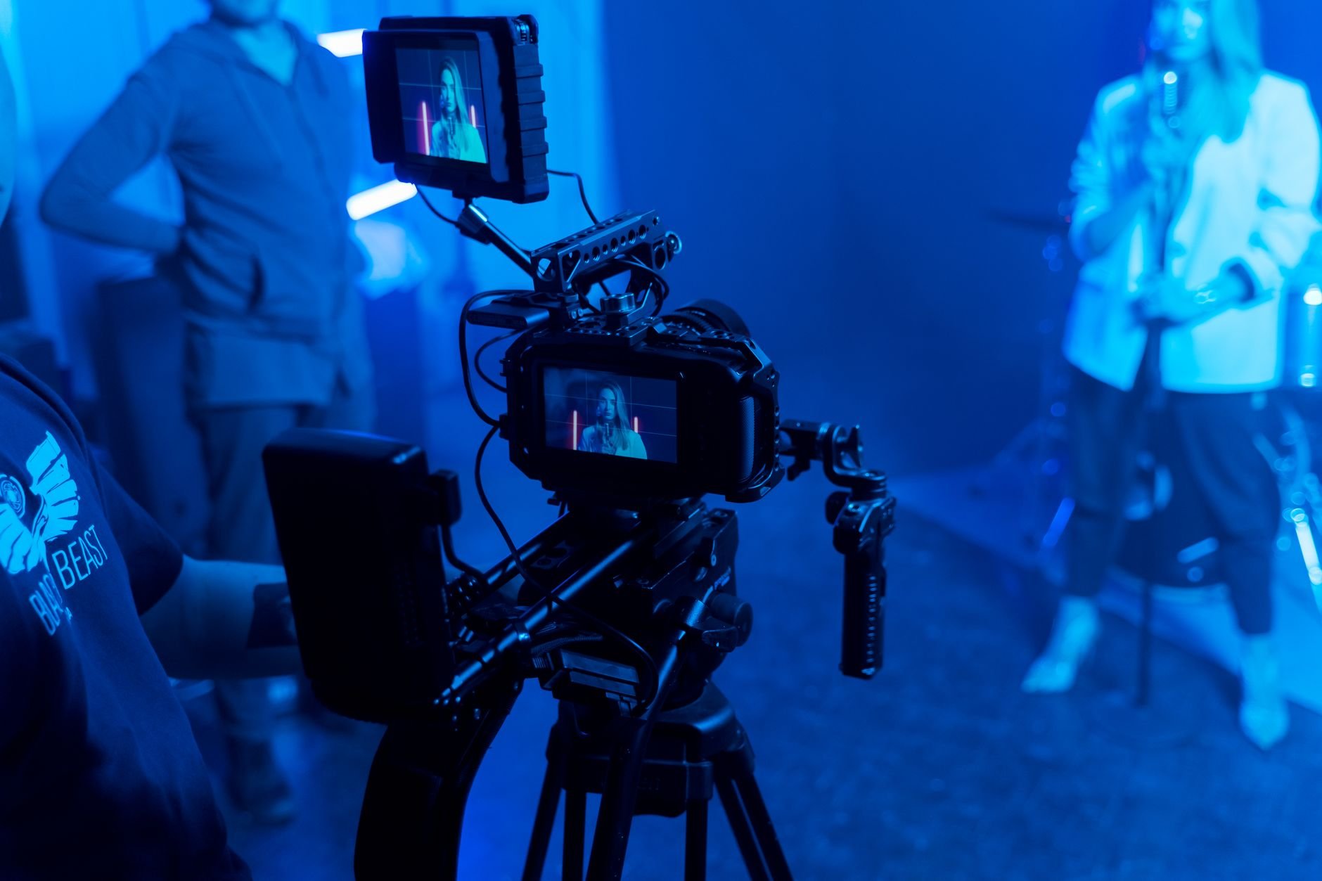 Behind the scenes of a music video recording with professional film equipment and studio lighting.